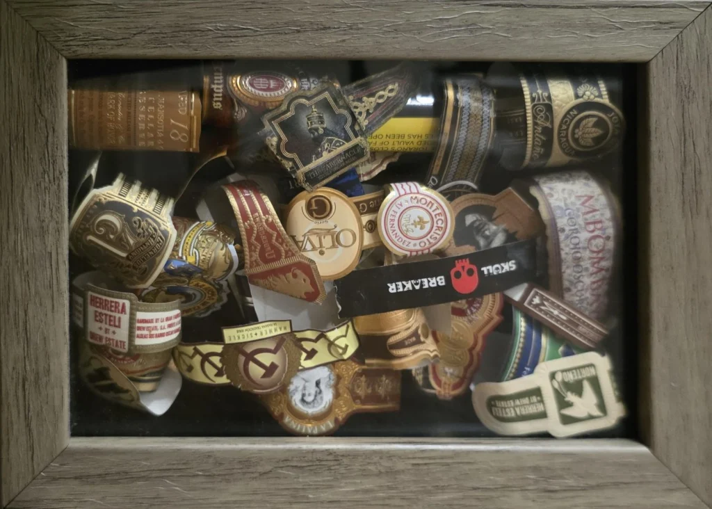 Shadow box filled with collected cigar bands in rows of gold, red and black